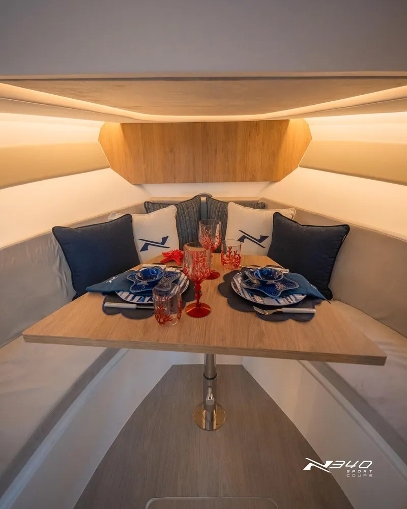 Slide: The Image of Luxurious dining setup inside 2025 NX Boats NX340 Sport cabin, featuring elegant tableware and cushions. - 3