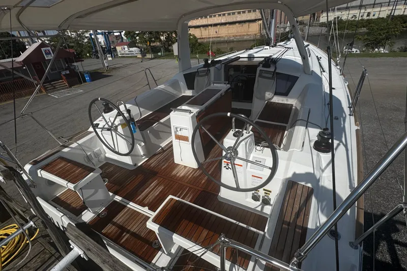 Slide: The Image of 2023 Beneteau Oceanis 38.1 cockpit with dual steering wheels and wooden table. - 10