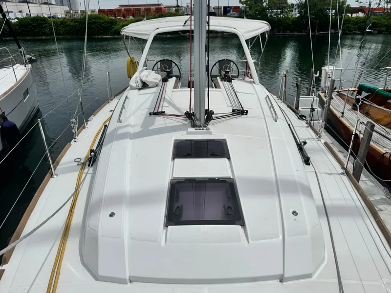 Slide: The Image of 2023 Beneteau Oceanis 38.1 yacht cockpit with canopy, docked near lush greenery. - 11