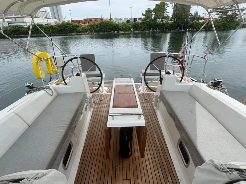 Slide: The Image of 2023 Beneteau Oceanis 38.1 sailboat cockpit with dual steering wheels and waterfront view. - 5