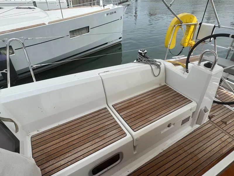 Slide: The Image of 2023 Beneteau Oceanis 38.1 sailboat cockpit with dual steering wheels and teak flooring. - 6