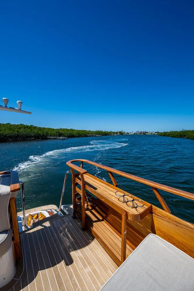 Slide: The Image of Hinckley Talaria 55 Flybridge MKII 2021 cruising on a sunny day, showcasing elegant wooden deck. - 18