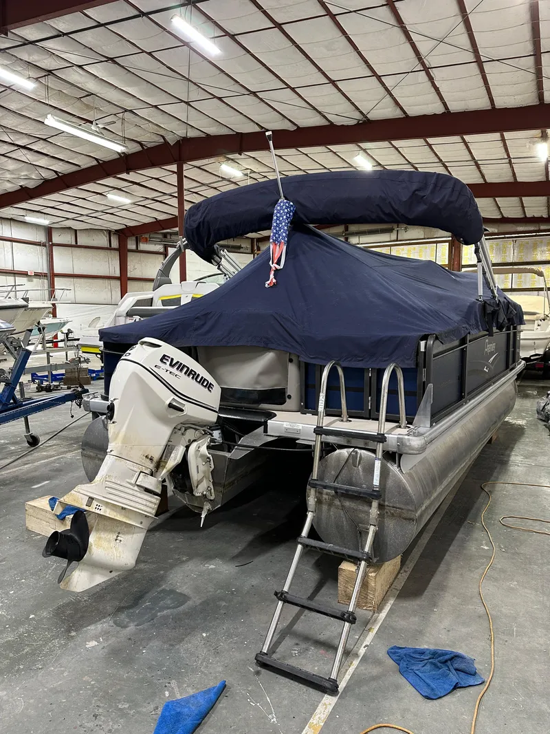 Slide: The Image of 2014 Premier 201 Explorer pontoon boat with Evinrude motor in a storage facility. - 2