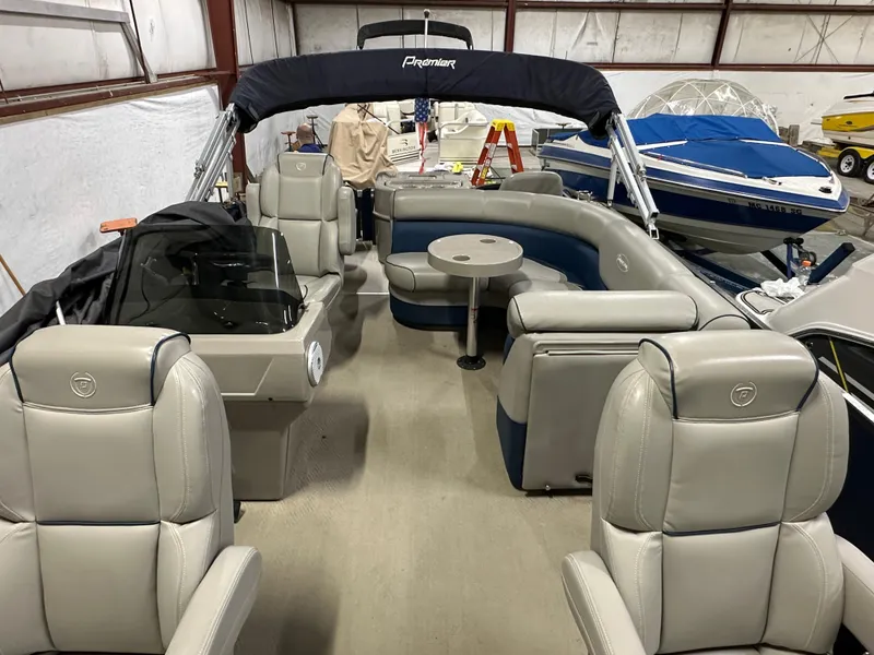 Slide: The Image of 2014 Premier 201 Explorer pontoon boat interior with seating and table in storage facility. - 6