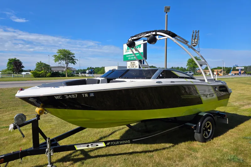 Slide: The Image of 2013 Four Winns H190RS boat on trailer, parked on grass under clear blue sky. - 5