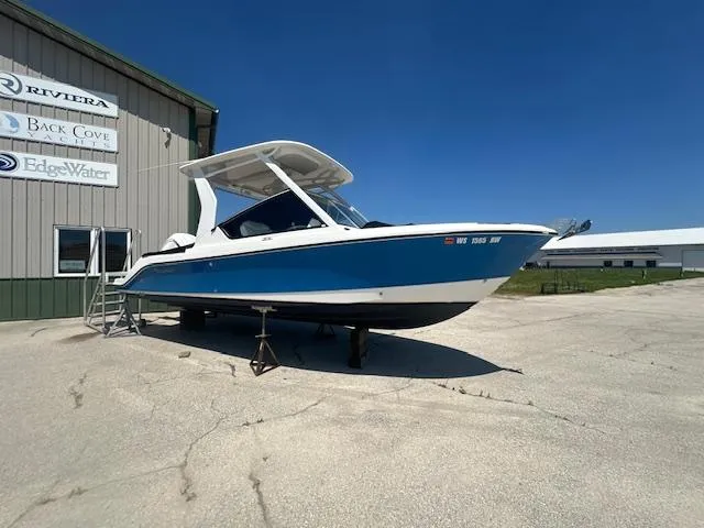 The Image of 2023 Edgewater 230CX boat displayed outdoors on a sunny day. - 0