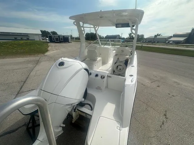 Slide: The Image of 2023 Edgewater 230CX boat with outboard motor, parked on a paved area. - 12