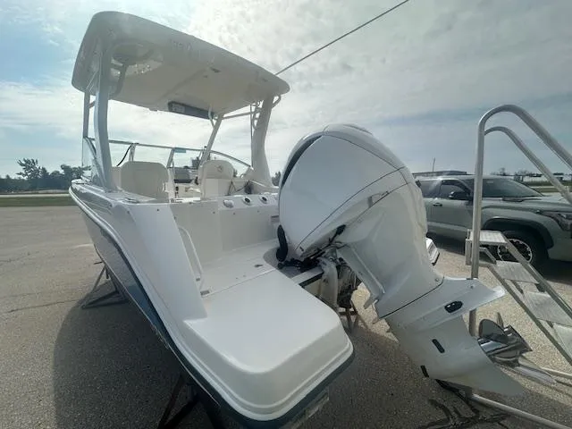 Slide: The Image of 2023 Edgewater 230CX boat displayed outdoors near a building under a clear blue sky. - 8