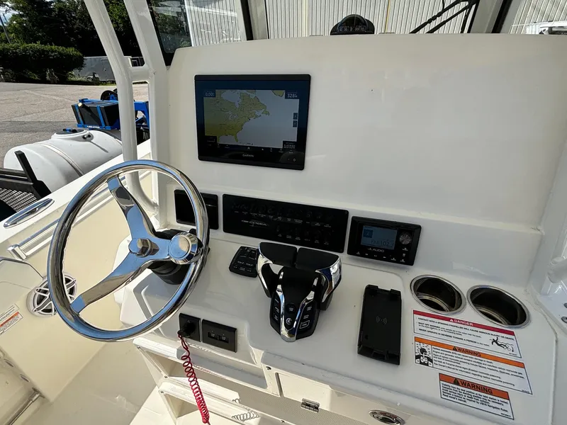 Slide: The Image of 2025 Cobia 265 Center Console boat dashboard with steering wheel and navigation display. - 16