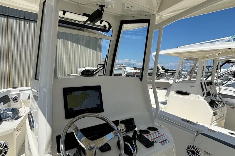 Slide: The Image of 2025 Cobia 265 Center Console boat interior with steering wheel and navigation display. - 18