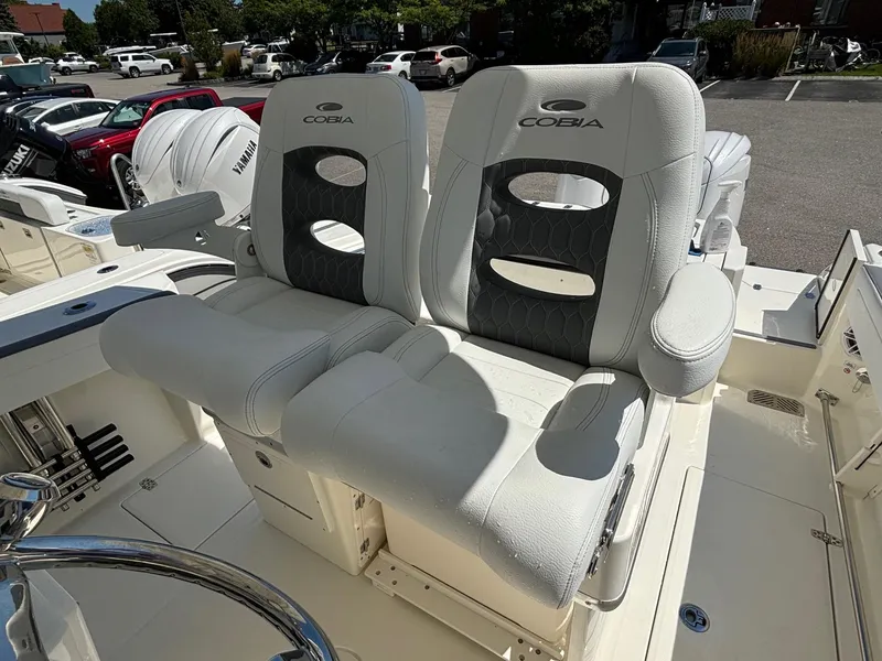 Slide: The Image of 2025 Cobia 265 Center Console boat seats, white and gray, in a parking lot. - 21