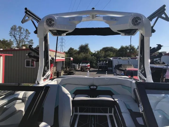 Slide: The Image of 2022 Centurion Ri 230 boat interior with speakers and seating, parked outdoors. - 32