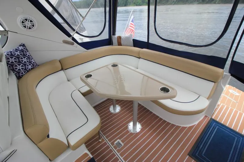 Slide: The Image of 2008 Four Winns V338 boat interior with cushioned seating and table, overlooking water. - 12