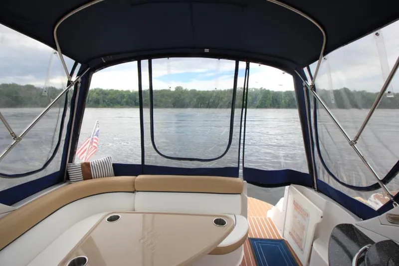 Slide: The Image of 2008 Four Winns V338 boat interior with lake view, featuring seating and table. - 13