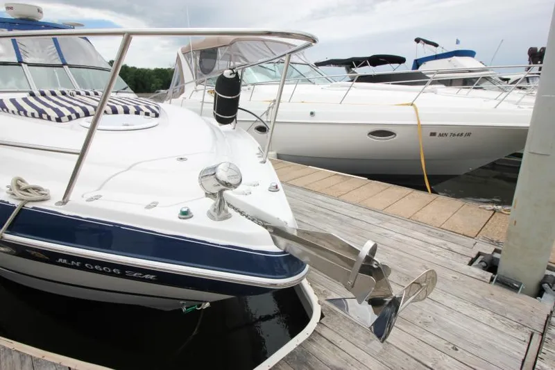 Slide: The Image of 2008 Four Winns V338 boat docked with anchor, featuring sleek design and striped cushions. - 4