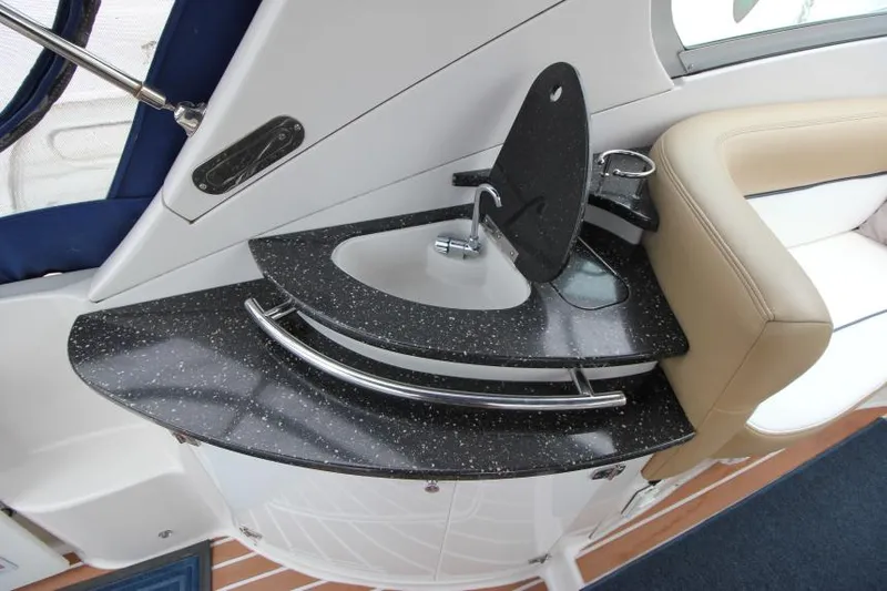Slide: The Image of 2008 Four Winns V338 boat interior with sleek black countertop and modern sink design. - 9