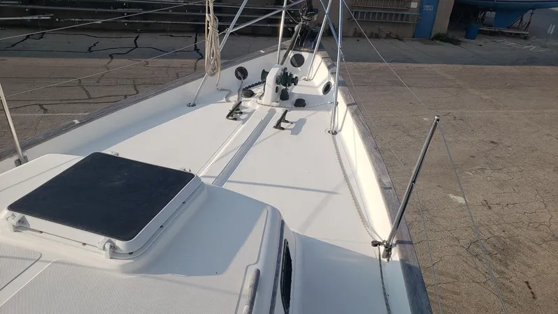 Slide: The Image of 1991 Pacific Seacraft 34 sailboat deck with rigging and hatch, docked on concrete. - 10