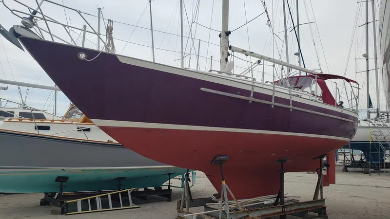 Slide: The Image of 1991 Pacific Seacraft 34 sailboat on dry dock, featuring a red hull and white trim. - 2