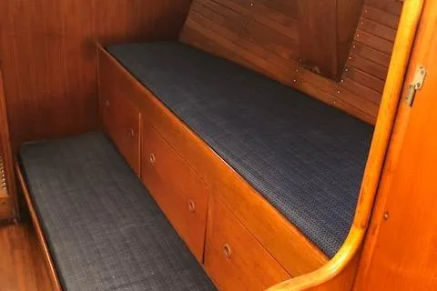Slide: The Image of 1972 Fastnet Lecomte interior with wooden cabinetry and blue cushioned seating. - 14