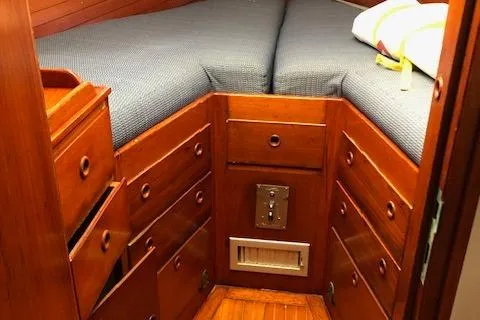Slide: The Image of 1972 Fastnet Lecomte boat interior with wooden drawers and cushioned bed. - 16