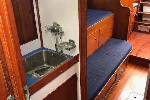 Slide: The Image of 1972 Fastnet Lecomte yacht interior with sink, blue cushions, and wooden cabinetry. - 18