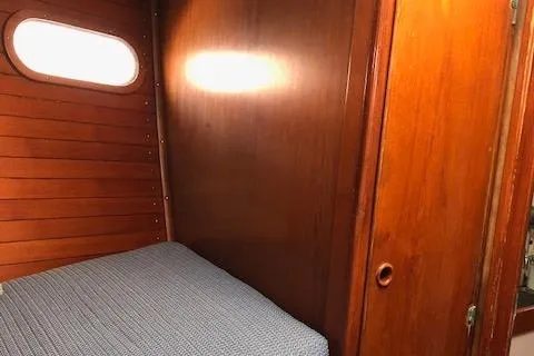 Slide: The Image of Wood-paneled cabin interior of a 1972 Fastnet Lecomte sailboat with a cozy bed. - 19