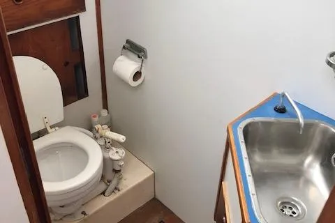 Slide: The Image of 1972 Fastnet Lecomte boat bathroom with toilet, sink, and wooden accents. - 22