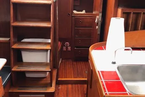 Slide: The Image of Interior of a 1972 Fastnet Lecomte sailboat with wooden cabinetry and red-tiled countertop. - 23