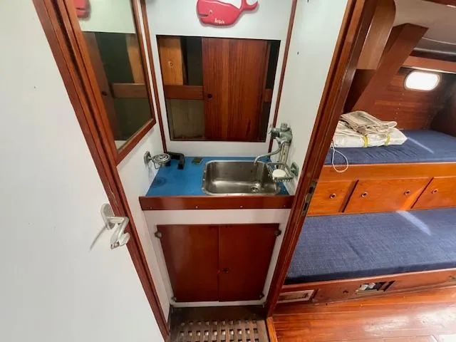 Slide: The Image of 1972 Fastnet Le Comte yacht interior with sink, wooden cabinetry, and blue cushioned seating. - 7