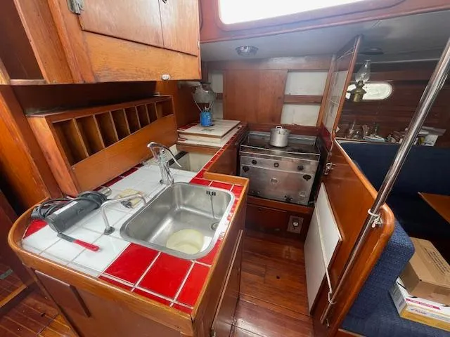 Slide: The Image of 1972 Fastnet Le Comte yacht kitchen with red-tiled counters and wooden cabinetry. - 9