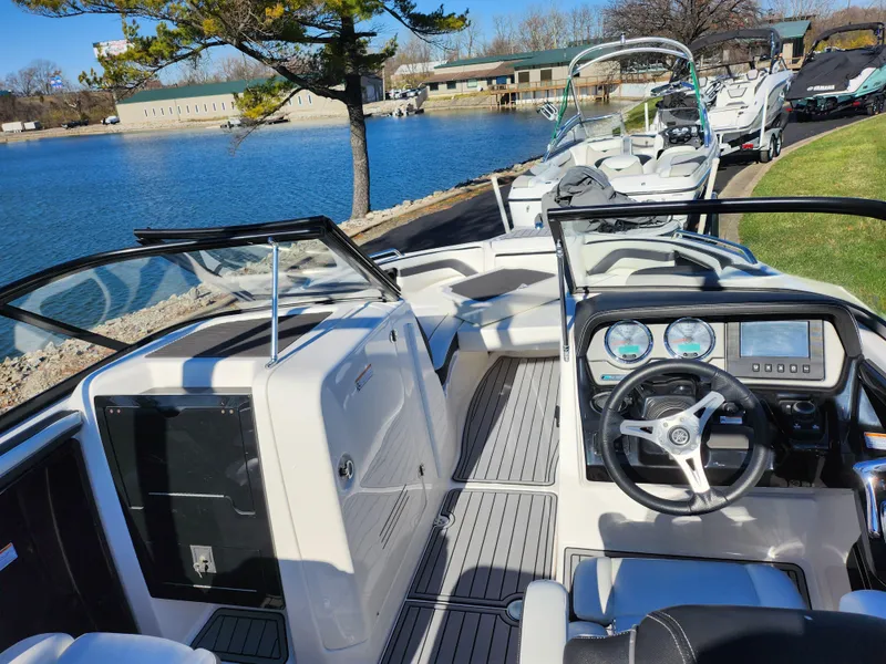 Slide: The Image of 2016 Yamaha Boats 242 Limited S interior with dashboard, docked by a serene lake. - 11