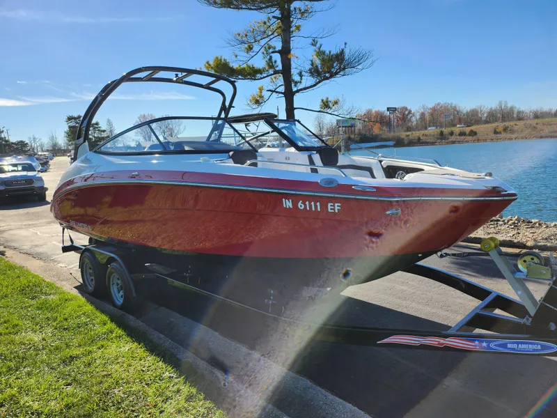 Slide: The Image of 2016 Yamaha Boats 242 Limited S on trailer by lakeside, sunny day. - 8