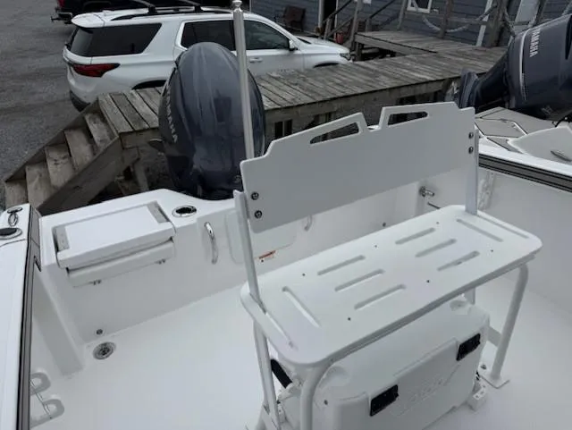 Slide: The Image of 2025 Wellcraft 202 Fisherman boat interior with seating and motor, docked near a white SUV. - 7