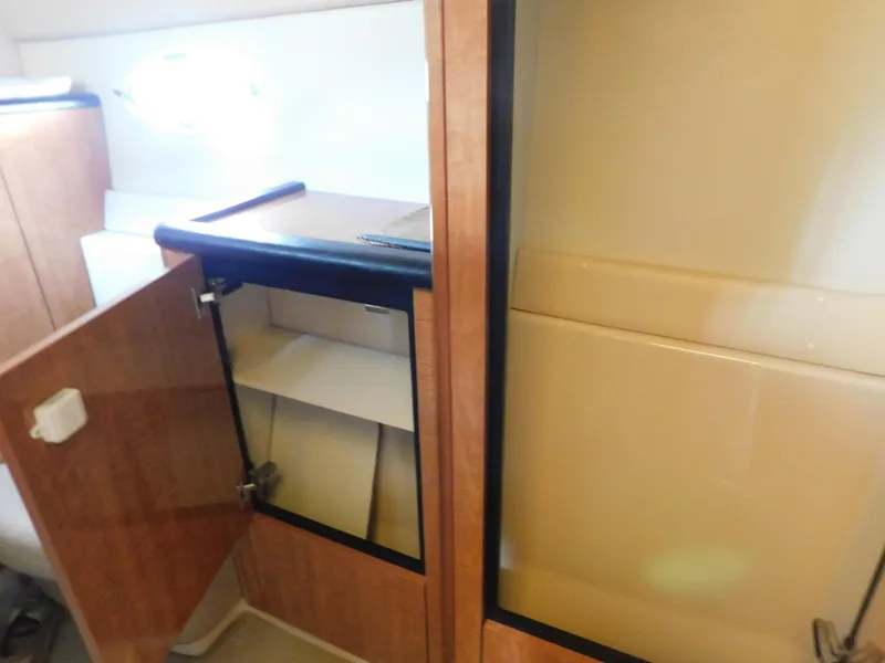 Slide: The Image of 2003 Maxum 3500 SY interior cabinet with open wooden door and shelves. - 28