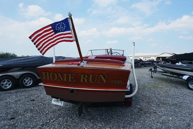 Slide: The Image of 1956 Chris-Craft Continental boat named "Home Run" with American flag, parked outdoors. - 15