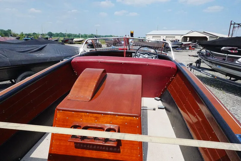 Slide: The Image of 1956 Chris-Craft Continental boat interior with wooden and red leather details, parked outdoors. - 7