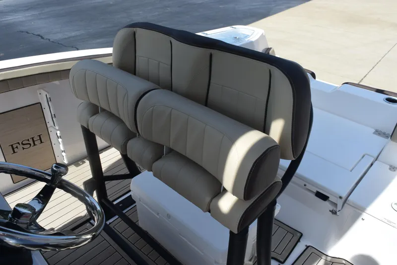 Slide: The Image of 2024 Yamaha Boats 255 FSH Sport H helm seating with beige upholstery and steering wheel. - 11