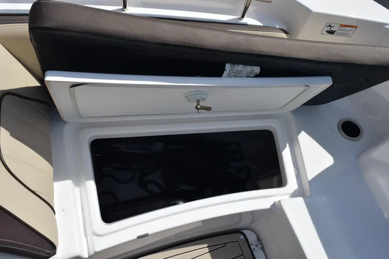 Slide: The Image of 2024 Yamaha Boats 255 FSH Sport H storage compartment with open lid, showcasing interior space. - 21