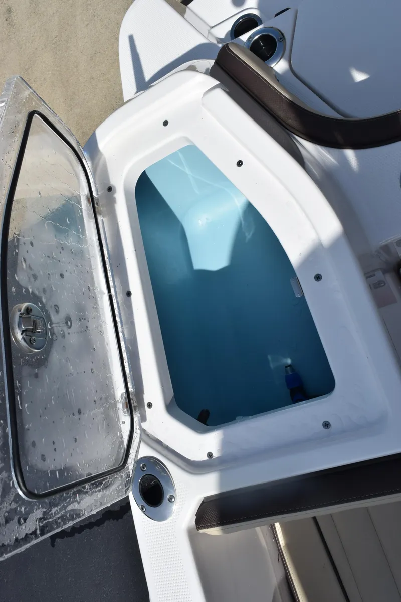 Slide: The Image of 2024 Yamaha Boats 255 FSH Sport H open storage compartment with water droplets on lid. - 24