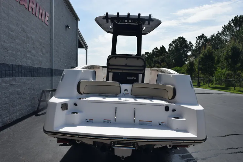 Slide: The Image of 2024 Yamaha Boats 255 FSH Sport H, rear view, parked outdoors near a building. - 5