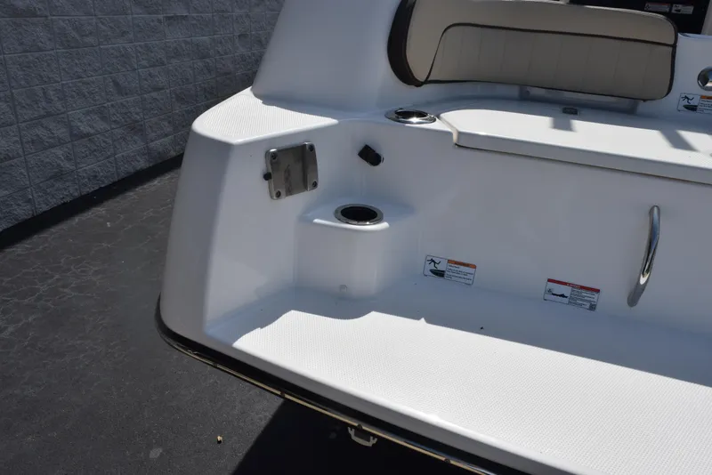 Slide: The Image of 2024 Yamaha Boats 255 FSH Sport H, rear seating area with cup holder and safety labels. - 8