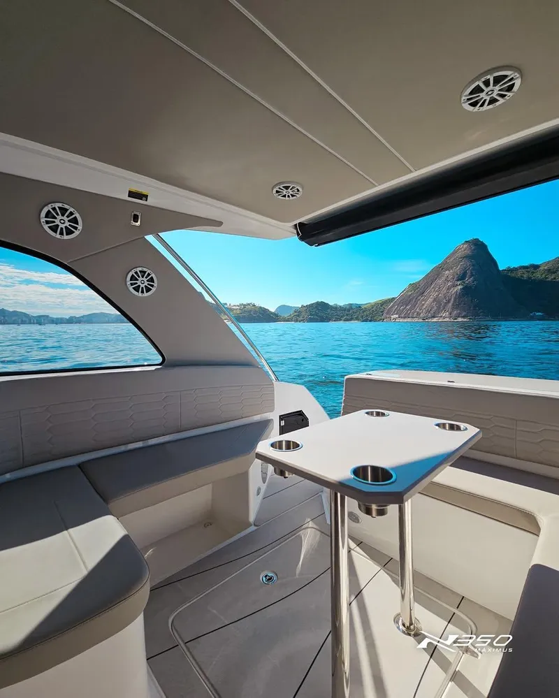 Slide: The Image of Interior of 2025 NX Boats NX350, featuring seating and table, with scenic ocean view. - 4
