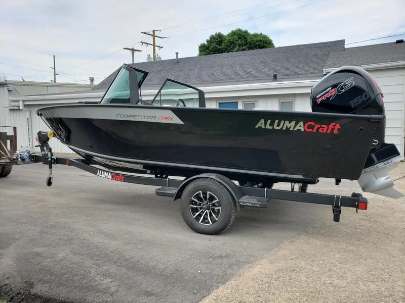 The Image of 2025 Alumacraft Competitor 175X Sport boat on trailer, black exterior, parked outdoors. - 0