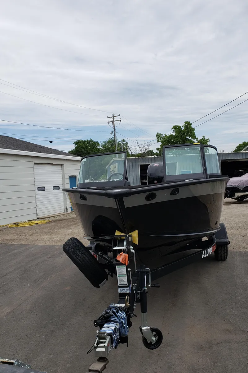 Slide: The Image of 2025 Alumacraft Competitor 175X Sport boat on trailer, parked outdoors. - 1