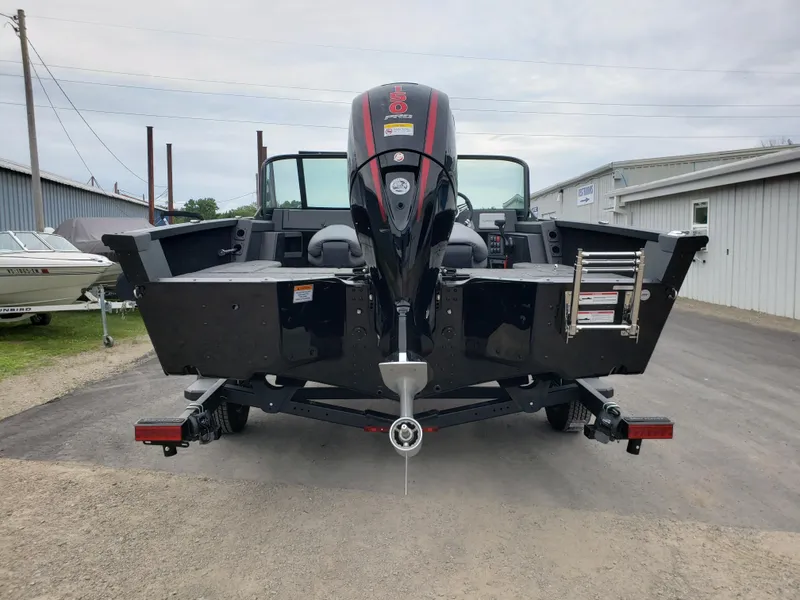Slide: The Image of 2025 Alumacraft Competitor 175X Sport boat, rear view with outboard motor and trailer. - 2