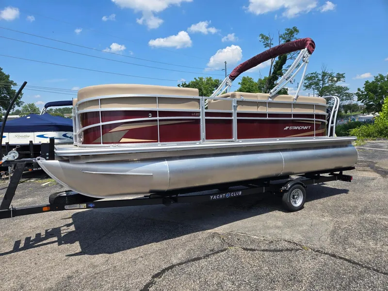 Slide: The Image of 2026 Starcraft LX20R pontoon boat on trailer, parked outdoors under blue sky. - 3