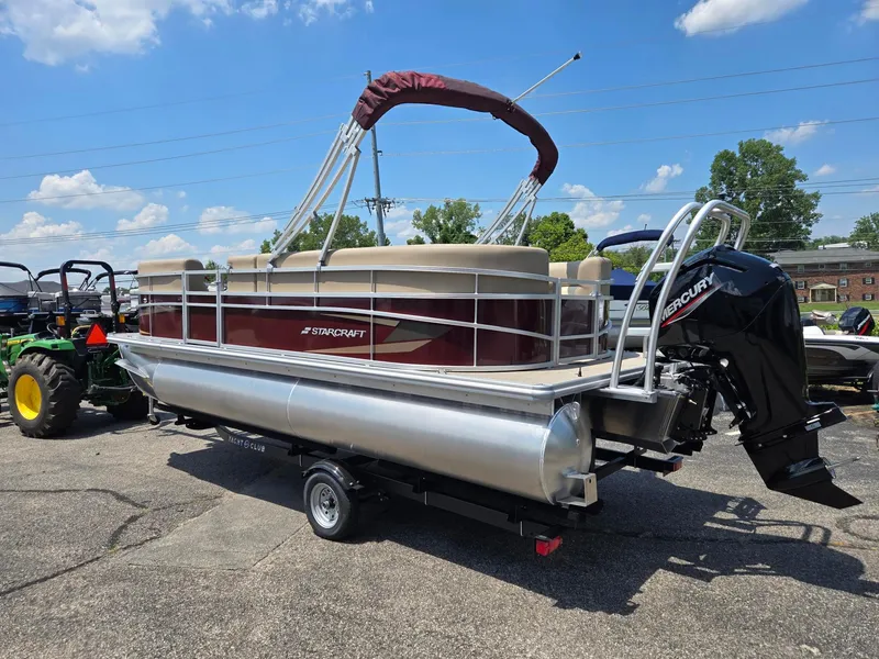 Slide: The Image of 2026 Starcraft LX20R pontoon boat with Mercury outboard motor on a trailer, parked outdoors. - 4