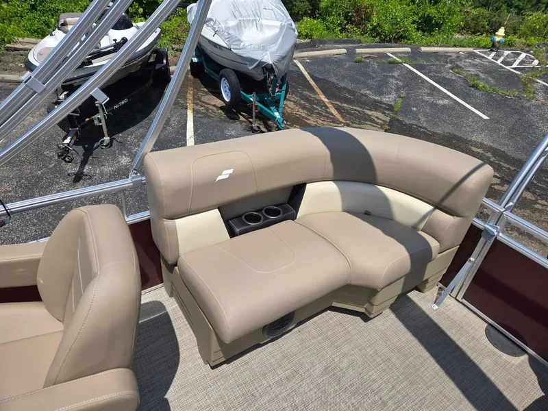 Slide: The Image of 2026 Starcraft LX20R boat interior with beige seating and cup holders in a parking lot. - 6