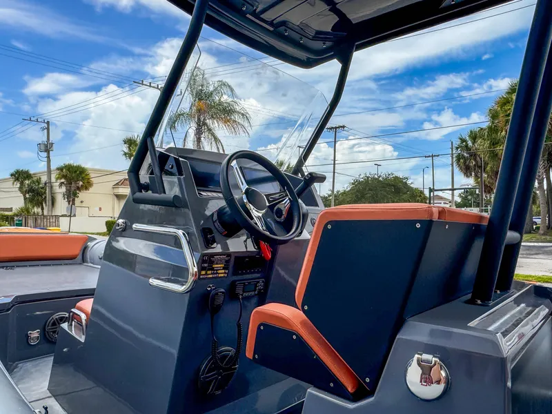 Slide: The Image of 2023 Northstar Orion 7 boat interior with steering wheel and dashboard, under a clear blue sky. - 2