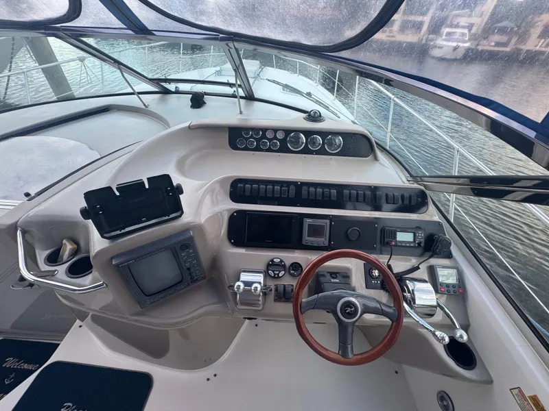 Slide: The Image of 1999 Sea Ray 400 Sundancer helm with navigation instruments and steering wheel, docked by the water. - 6